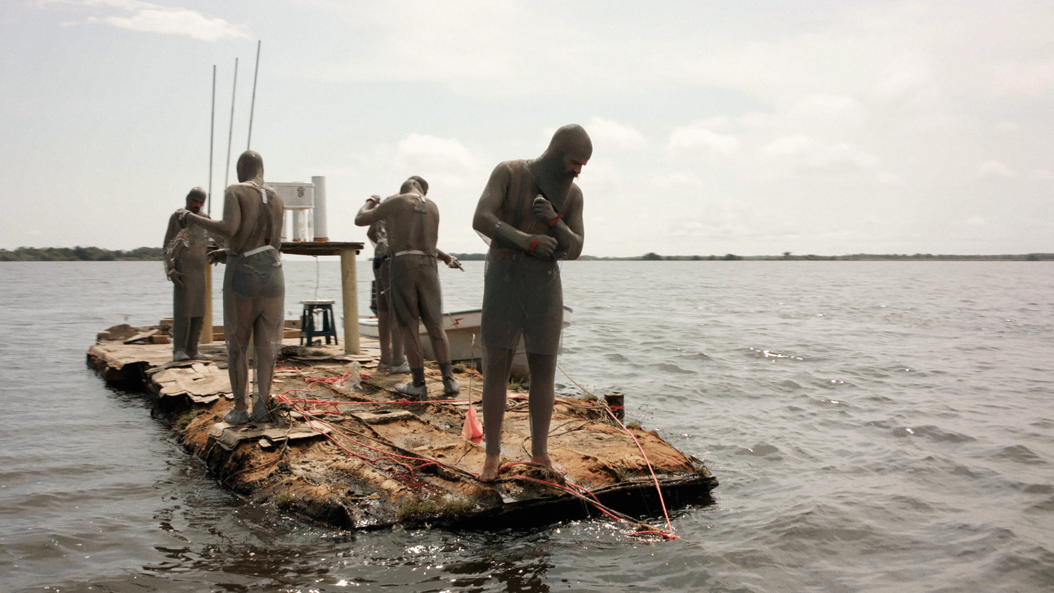 Vier Männer in Kettenhemden auf einem Floss am Meer