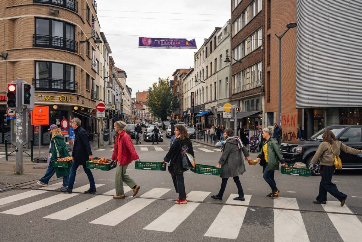 Menschen gehen mit Transparenten nacheinader über einen Zebrastreifen