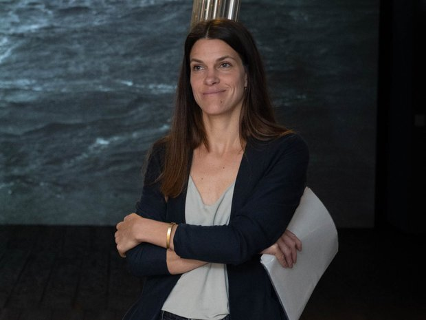 Frau mit dunkeln Blaser und verschreckten Armen, dunkle lange braune Haare, lächelnd