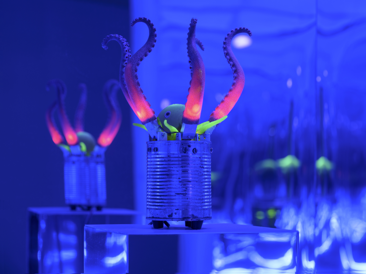 Mechanische Otopusarme ragen aus einer Blechdose auf einem Podest, umgeben von reflektierenden Wänden