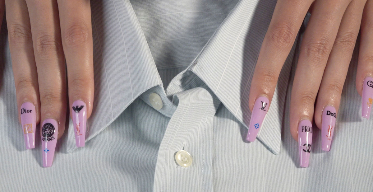 Hemdkragen, die Hände an den Seiten; lange Fingernägel, hellrosa Nagellack und schwarze Markenlogos