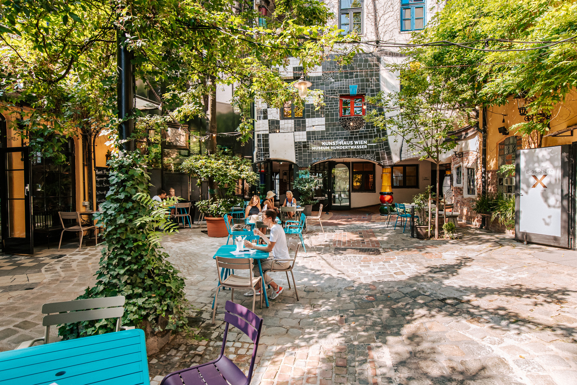 Foto vom sonnigen Innenhof des KunstHausWien mit Cafe Tischen und Sesseln