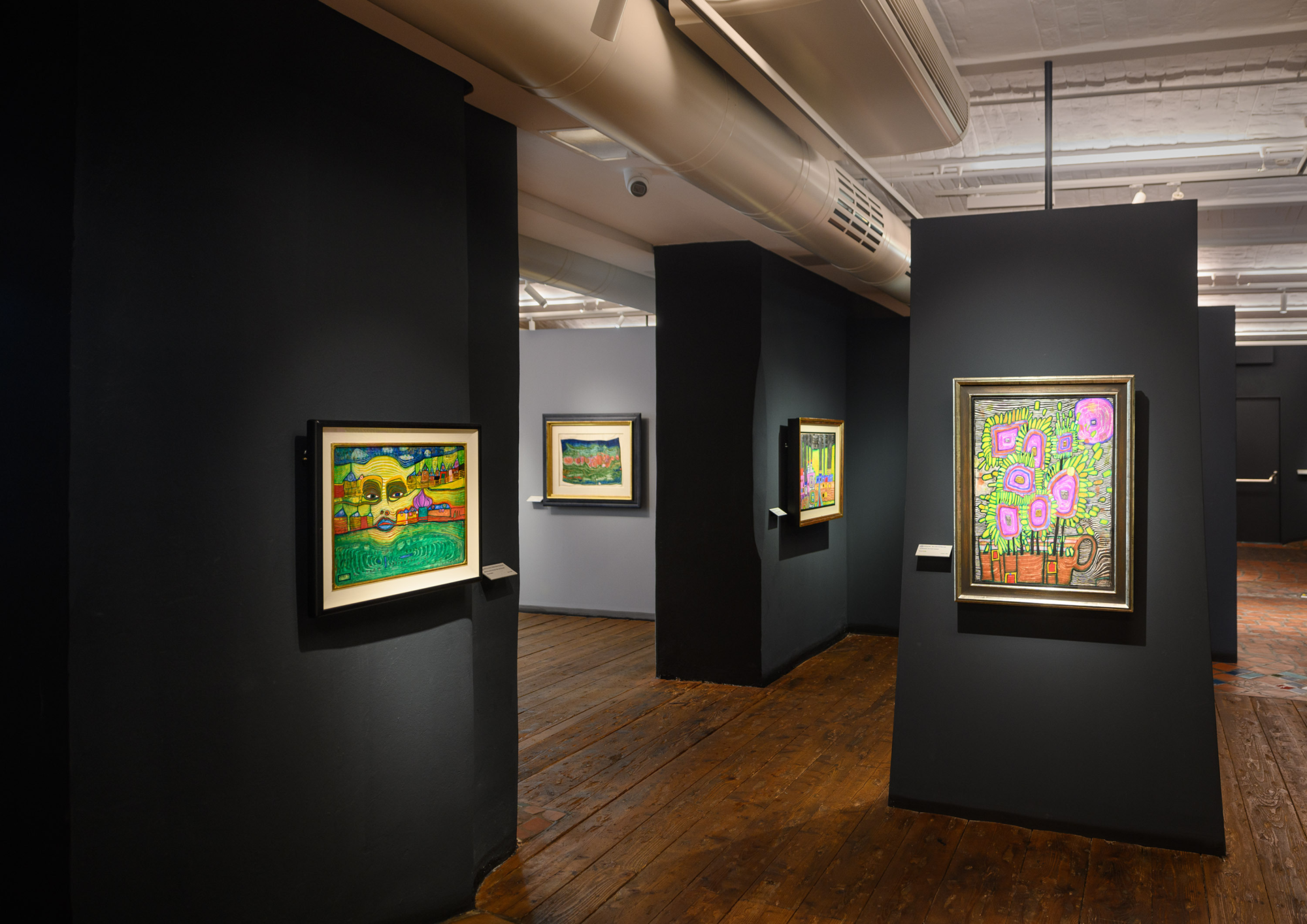 Ausstellungsansicht in das Museum Hundertwasser mit Holzboden und bunten Bildern an den Wänden