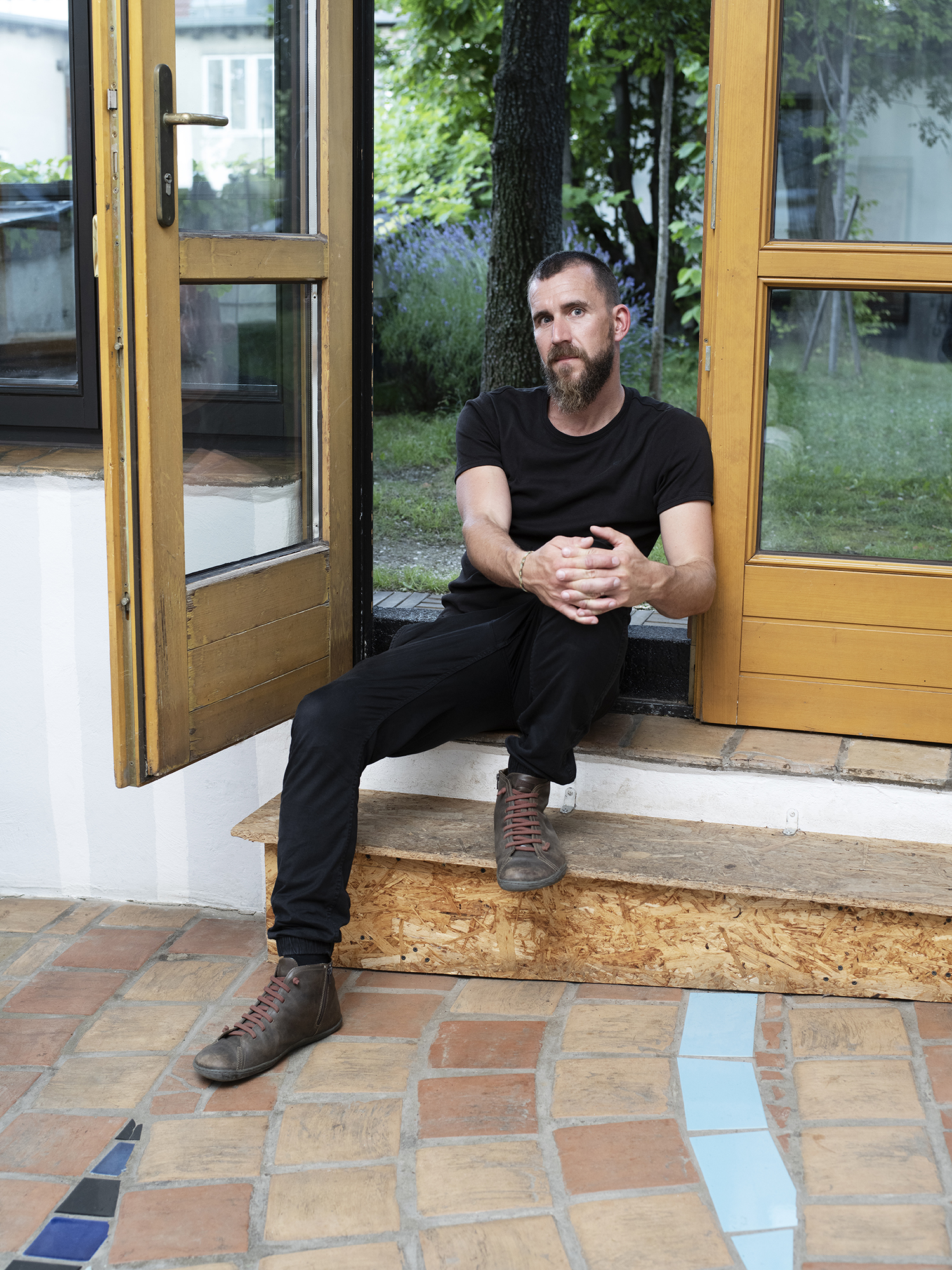 Der Künstler Gregor Sailer sitzt auf der Terrassentreppe der Hundertwasser-Wohnung