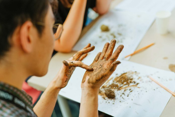 Person von hinten mit Erde an den Händen